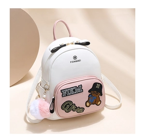Close-up of mini backpack showing cute bear embroidery and decorative fuzzy ball charm