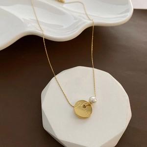Titanium steel gold coin necklace with white pearl on minimalist stone display