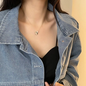 Minimalist titanium steel necklace with coin pendant and pearl, worn by a model
