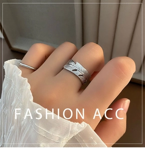 Macro shot of silver feather open ring and minimalist band on finger with lace sleeve