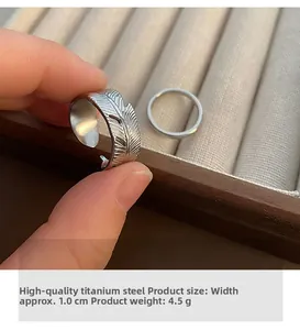 Detail showing carved feather ring and minimalist band in premium titanium steel