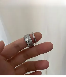 Detailed close-up of a silver feather-shaped open ring featuring intricate textures