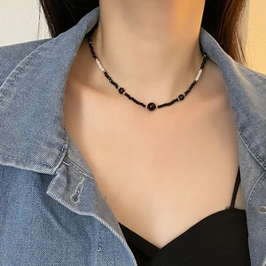 Elegant black beaded necklace with white pearls and gold spacers on a female model