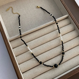 Elegant beaded necklace with black spinel and white pearls in a wooden jewelry box