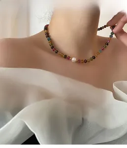 Détail d'un collier en perles de tourmaline colorées avec perle blanche sur un mannequin