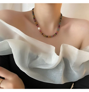 Détail d'un collier de perles en pierres naturelles colorées avec perle blanche sur un mannequin