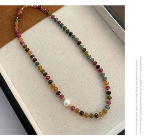 Détail d'un collier de pierres naturelles avec une perle d'eau douce et séparateurs dorés