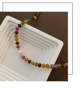 Détail d'un collier en pierres naturelles avec perle blanche et entretoises dorées sur socle