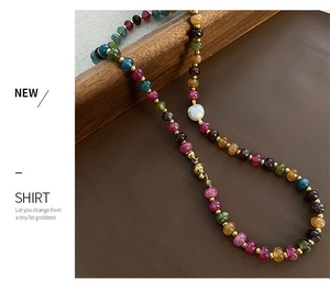 Détail d'un collier artisanal en pierres naturelles avec perles dorées et perle blanche centrale