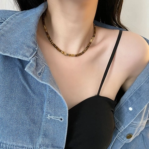 Vintage tiger eye beaded necklace with gold metal accents on a model in denim jacket