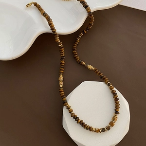 Tiger eye stone beaded necklace with golden accents on white geometric stand