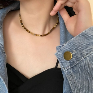 Tiger eye stone beaded necklace with gold metal accents worn by a model in denim