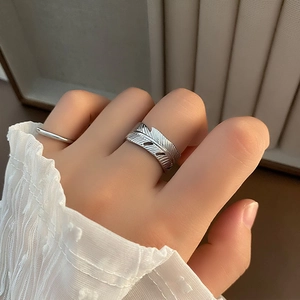 Silver feather open ring set with minimalist band on hand against white lace