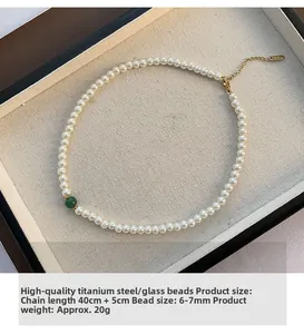 Detail of pearl necklace with green bead and gold-plated titanium steel clasp on tray