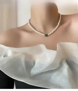 French pearl necklace with central green bead and golden spacers on female model