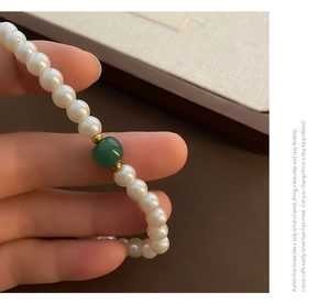 Close-up of French glass pearl necklace with green agate bead and gold spacers