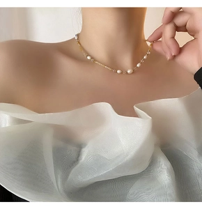 Close-up of pearl necklace with yellow beads on model with white ruffled shirt