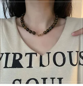 Tiger eye bead necklace with 8-10mm stones and gold clasp worn on model outfit