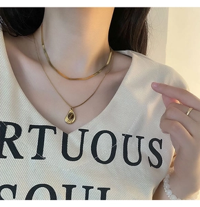 Detailed view of layered gold necklace with tiger eye pendant and flat snake chain