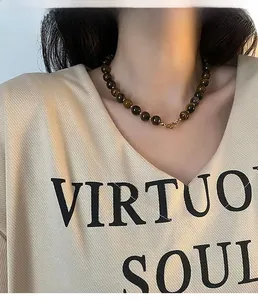 Macro view of a tiger eye stone bead necklace with a golden clasp on model neck