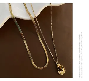 Close-up of gold snake chain with a tiger eye stone teardrop pendant in vintage style