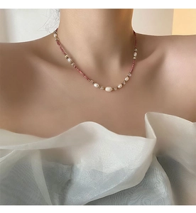 Detail of pink natural stone and baroque pearl necklace worn on model neck