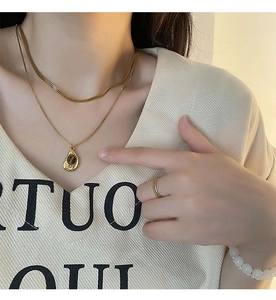 Detailed close-up of double-layered gold necklace with a water-drop gemstone pendant