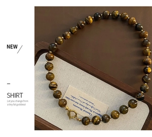 Tiger eye stone beaded necklace with golden toggle clasp on a vintage wood tray