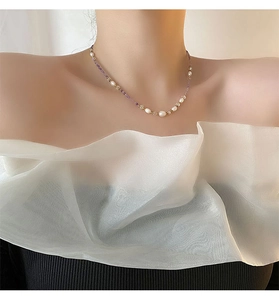Detail of natural pearls and purple beads necklace on female model collarbone