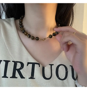 Detailed view of natural tiger eye stone beads necklace with gold accents on a model