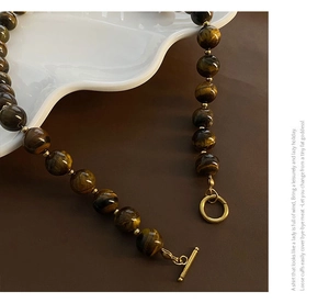 Detail of brown tiger eye beads with golden T-bar clasp and delicate metal spacers