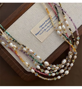 Detailed close-up of mixed natural stone and pearl choker necklace on a wooden tray