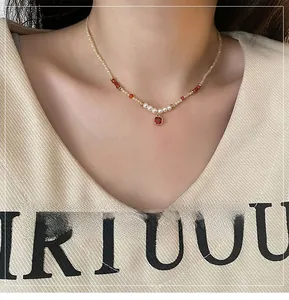 Détail d'un collier de perles, perles oranges et pendentif en pierre rouge pour femmes
