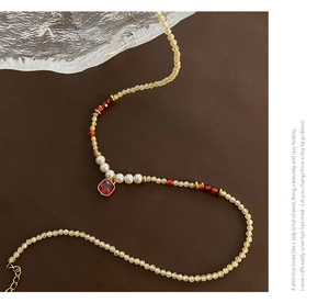 Détail macro du collier de perles en pierre naturelle avec pendentif rouge et fermoir doré