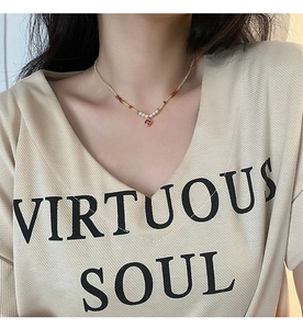 Détail d'un collier en pierres naturelles avec perles blanches et un pendentif rubis