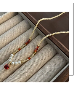 Vue macro d'un collier de perles avec pendentif rubis dans une boîte à bijoux en bois