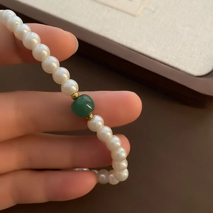 French glass pearl necklace with a central green bead and golden metal spacers