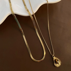 Golden herringbone chain and pendant necklace with tiger eye stone on aesthetic tray