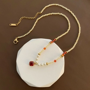 Collier en pierres naturelles avec pendentif carré rouge et perles sur plateau blanc