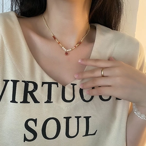 Collier en perles naturelles avec pendentif carré rouge sur le cou d'un mannequin femme
