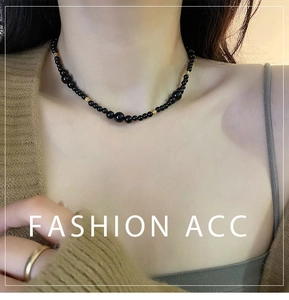 Close-up of black onyx beaded necklace with gold spacers on model wearing brown sweater