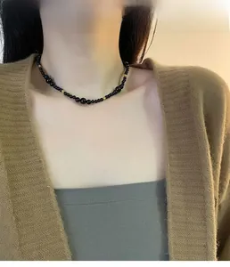 Detail of black onyx beaded necklace with gold accents worn on a model's neckline