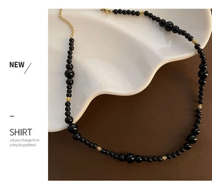 Macro shot of black agate beaded necklace with gold accents and lobster clasp detail
