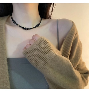 Detail of beaded necklace with black onyx beads and golden spacers on model collarbone