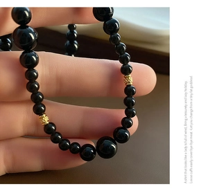 Detailed macro of black agate beaded necklace with gold engraved spacer beads