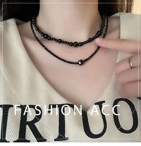 Close-up of double-layered black beaded necklace with faceted stone on a model