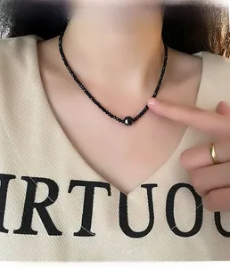 Detail of beaded black onyx choker featuring a faceted center bead on a model's neck