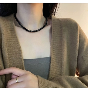 Close-up of minimalist black beaded choker necklace with high-gloss finish on model