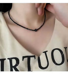 Detailed view of beaded black onyx necklace with central geometric bead on a model