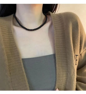 Detail of beaded black onyx necklace on model neck with minimalist round bead design
